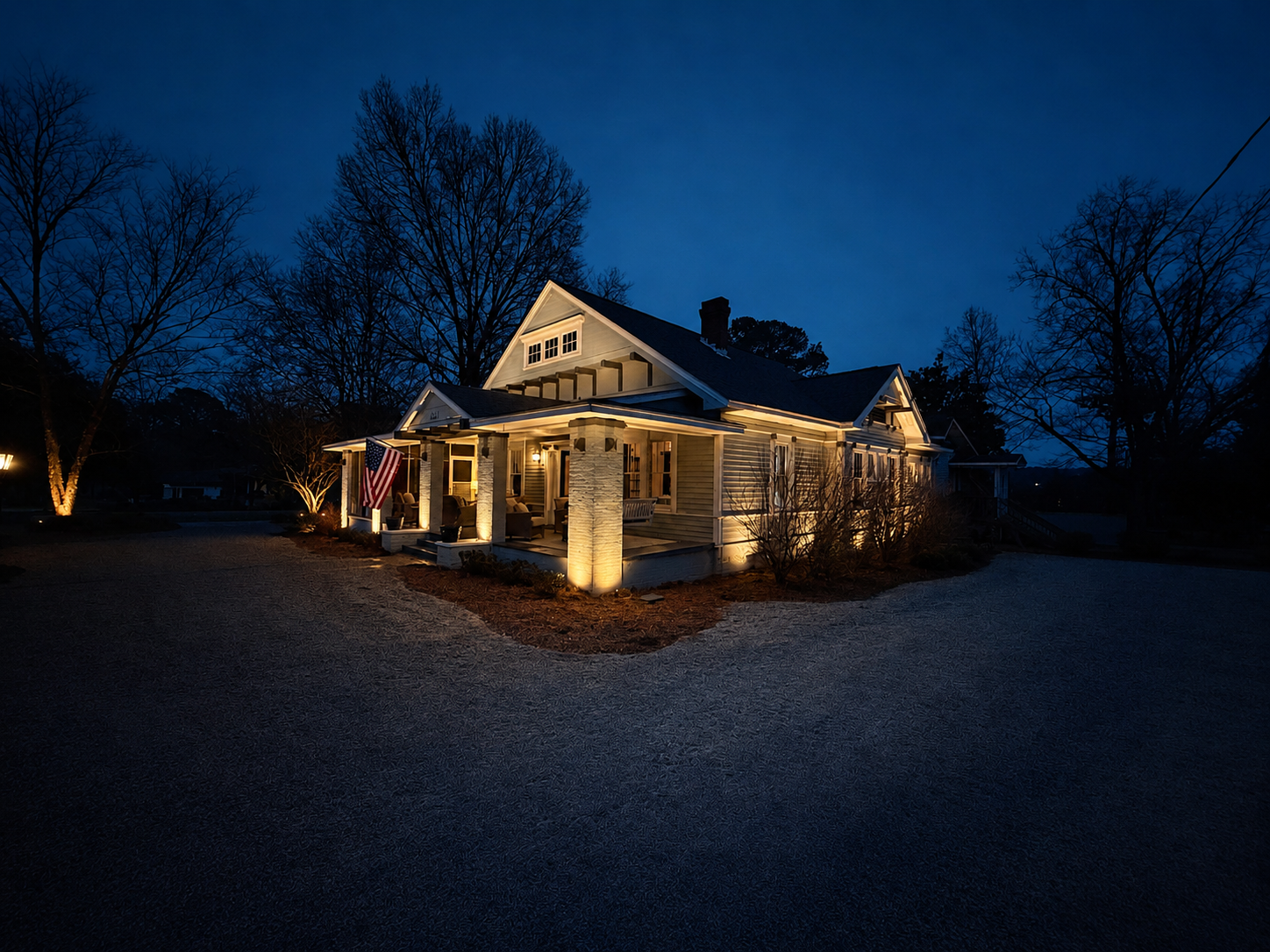 Modern farmhouse with full exterior uplighting at dusk
